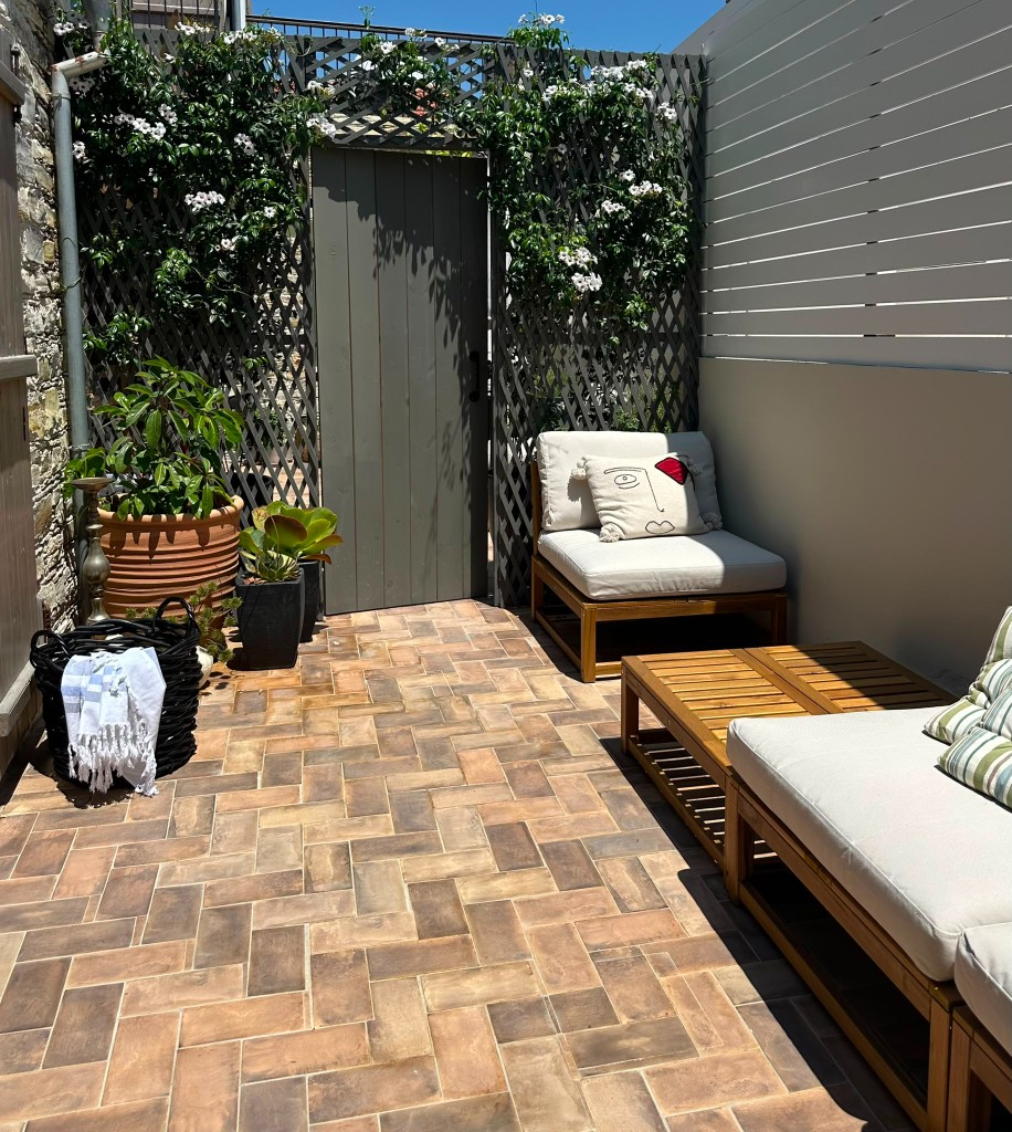 Cozy courtyard lounge with wooden furniture and floral trellis