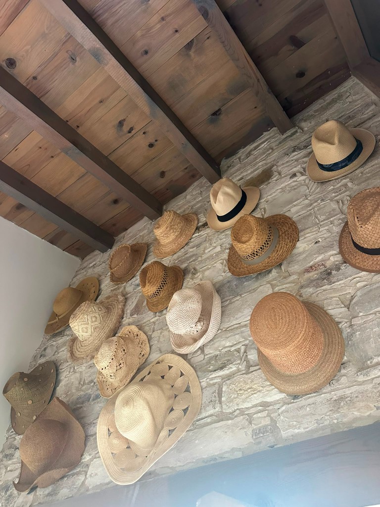 Decorative straw hats displayed on a traditional stone wall